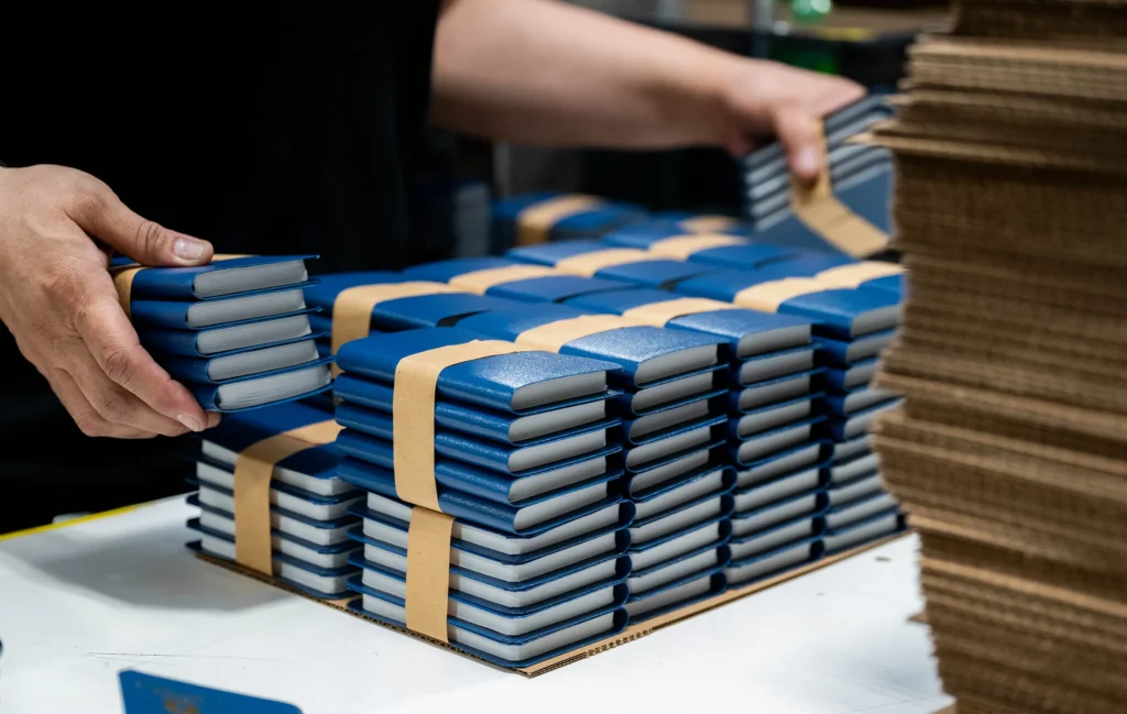Stacks of leather-bound bibles and devotional guides being prepared for distribution.