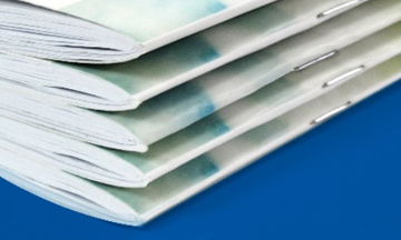 View of the exterior and interior spine of a thin booklet, showing two metal staples centered in the fold to secure the pages together.