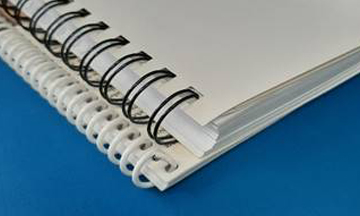Three different mechanical binding styles shown together: a black plastic coil, a silver twin-loop Wire-O, and a concealed Wire-O spine that is hidden inside a hard cover.