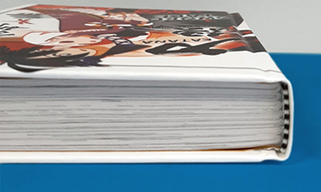 Overhead view of an open smyth-sewn hardcover book, showing the visible stitched signatures at the spine that allow the book to lay completely flat on a surface.