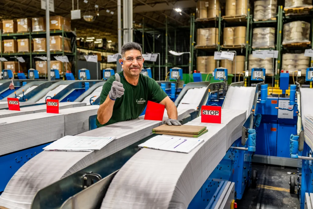 Lakeside Book employee monitoring a production line where hardcover books are being processed through automated industrial machinery.