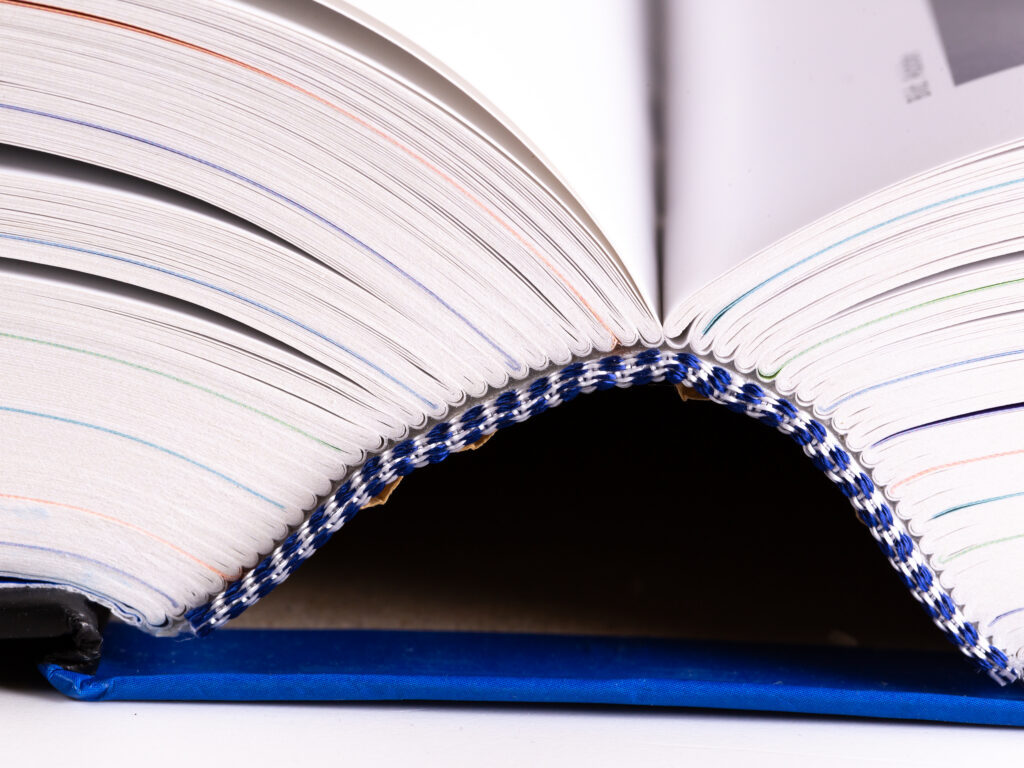 Close-up of a flex-bound book showing its flexible cardstock cover bending slightly while the pages remain flat, demonstrating its lightweight and pliable nature.